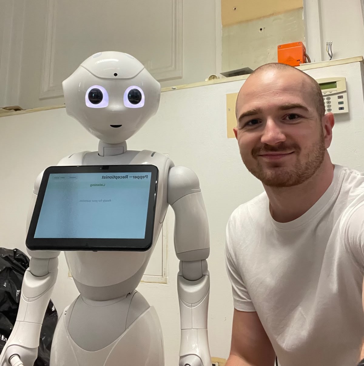 Lukas Navara standing beside the Pepper robot